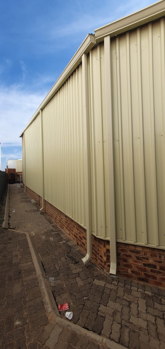 Long run of cream downpipes along the side of an industrial building